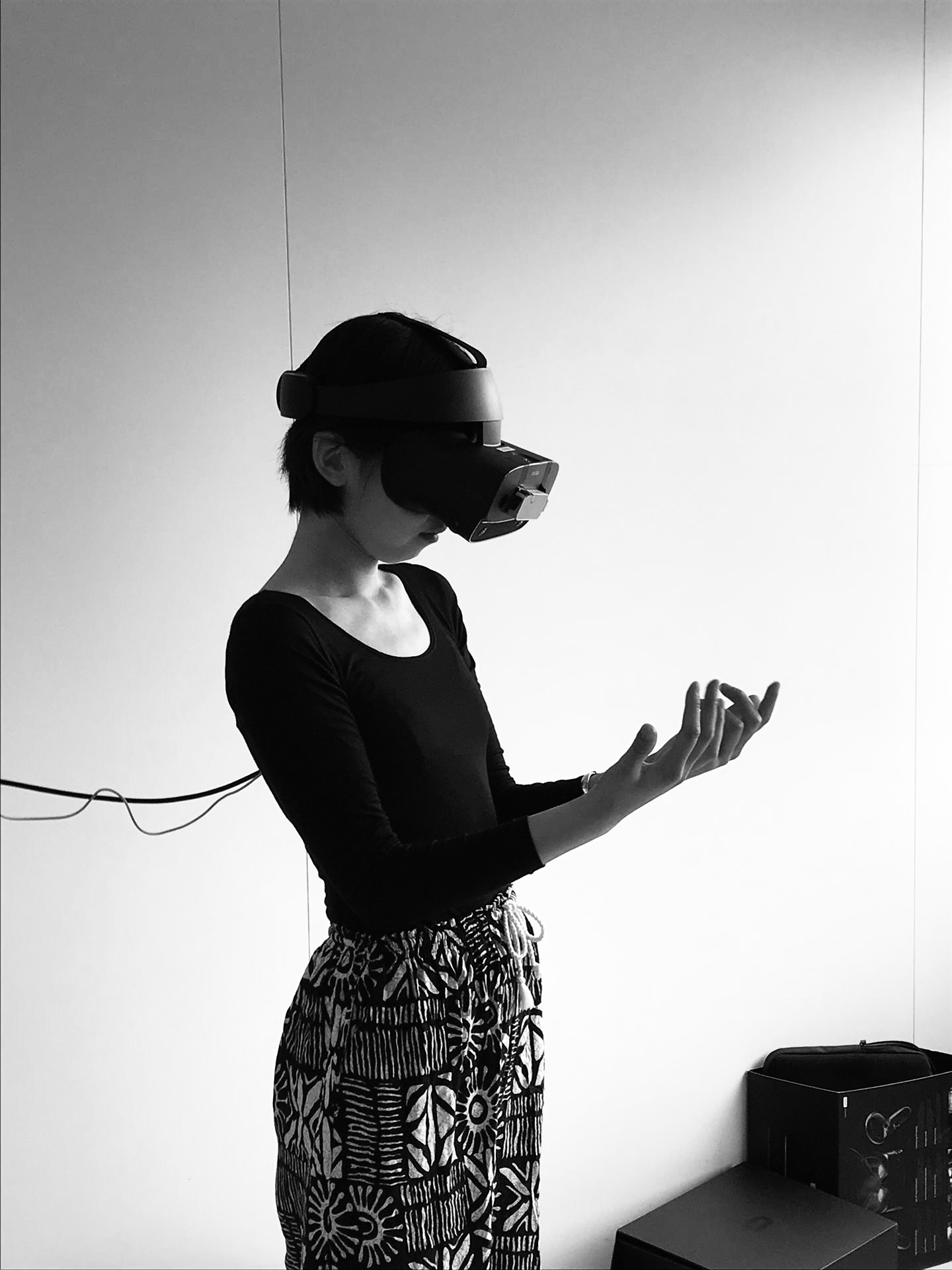 a chinese woman with short hair wearing a virtual reality headset looking at her hands through the sensors