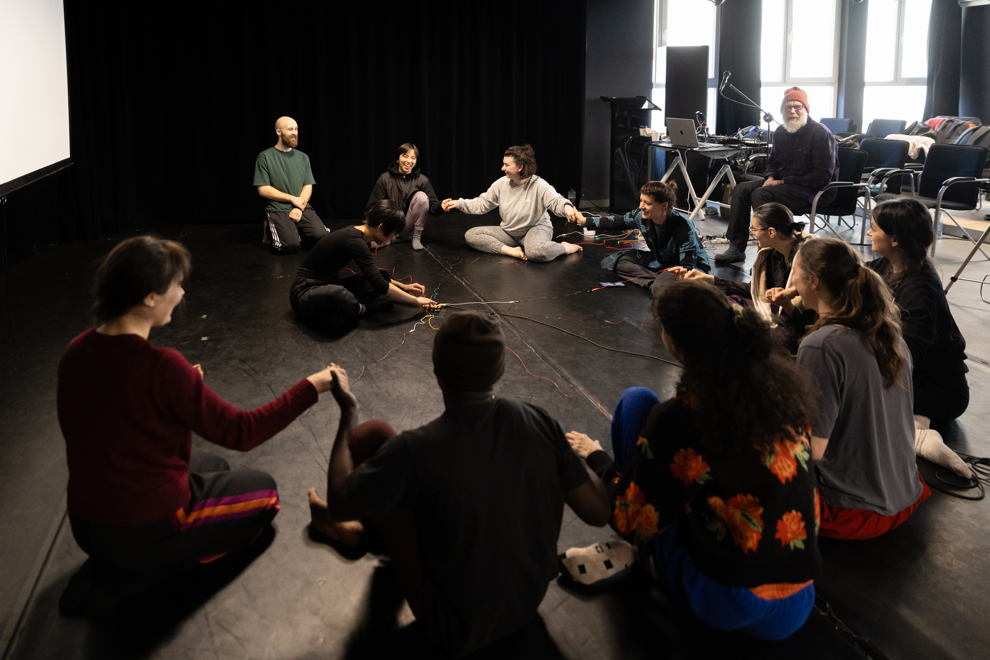 A group of people sitting in a circle connected with wires.