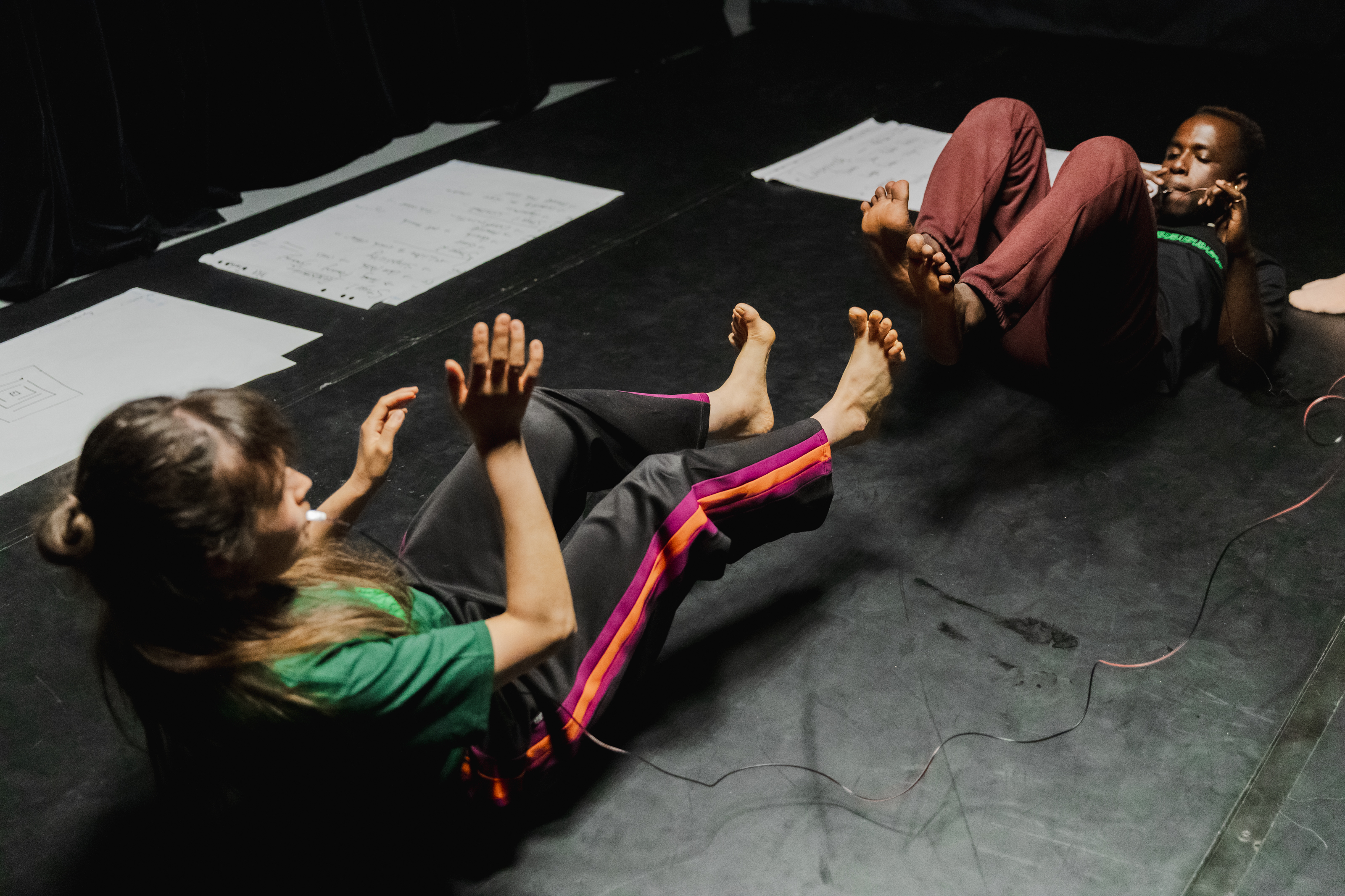 Two people lying on the floor with their toe almost touching each other.